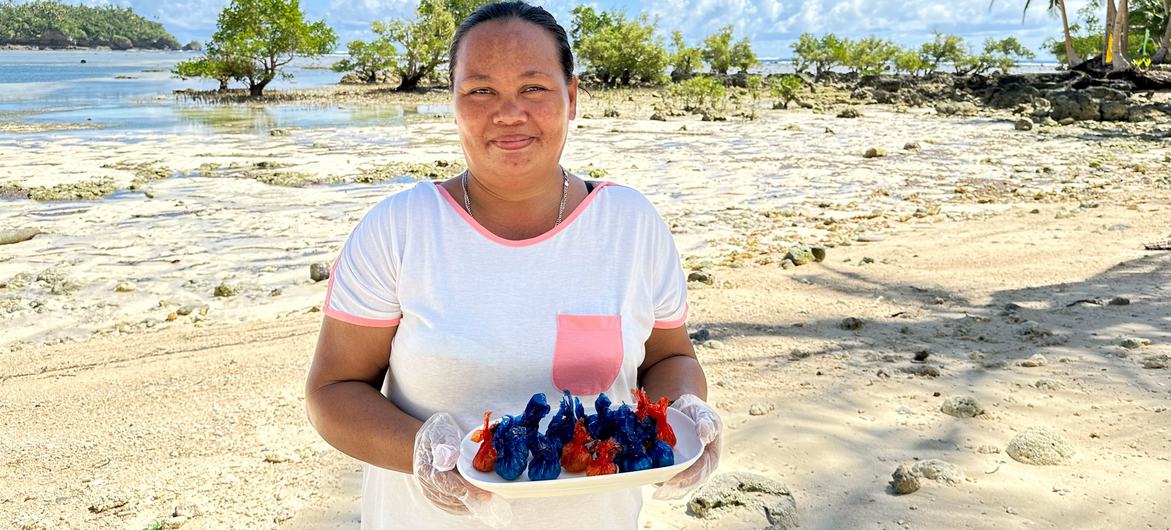 Alma Gonzales, une entrepreneuse spécialisée dans les bonbons à la noix de coco sur l'île isolée de Siargao, aux Philippines, se tient sur une plage, tenant une assiette de ses produits.