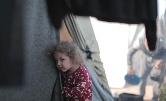 A young girl peers out from a tent in Gaza.