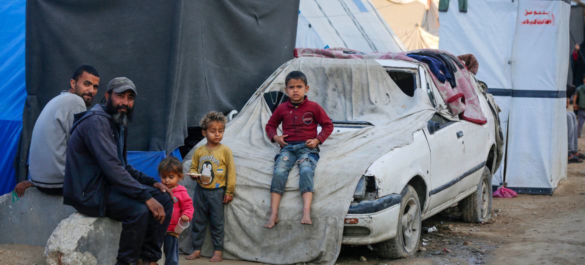 Una familia sentada frente a un refugio en Gaza.