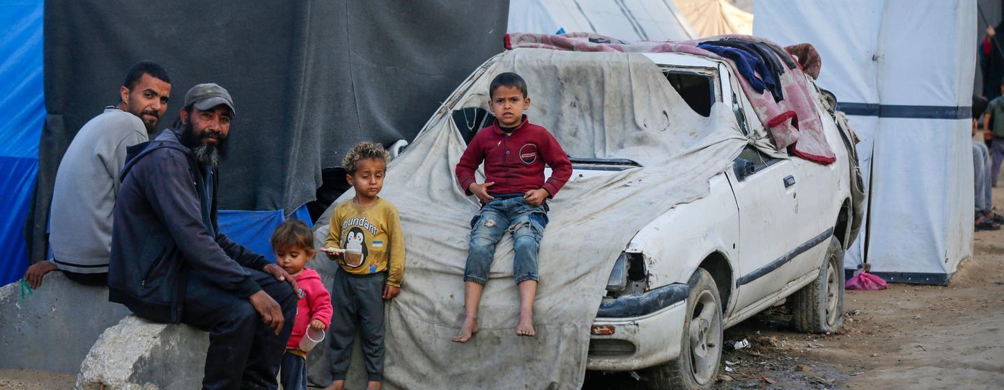 Une famille assise à l'extérieur d'un abri à Gaza.