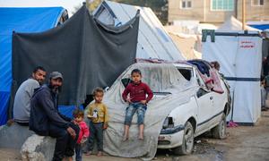 A family sits outside a shelter in Gaza.