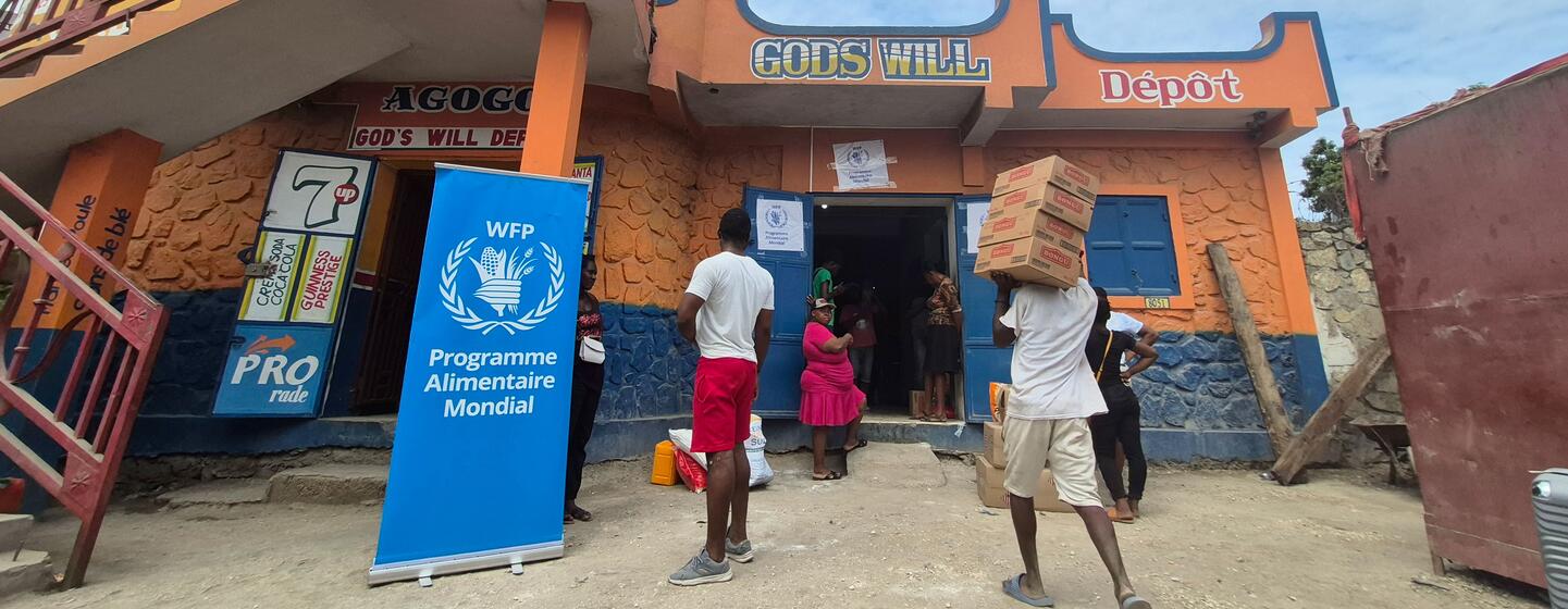 A family receives food assistance from the World Food Programme (WFP) in Haiti through a voucher system at a local store called 'God's Will Dépôt'.