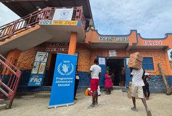 A family receives food assistance from the World Food Programme (WFP) in Haiti through a voucher system at a local store called 'God's Will Dépôt'.