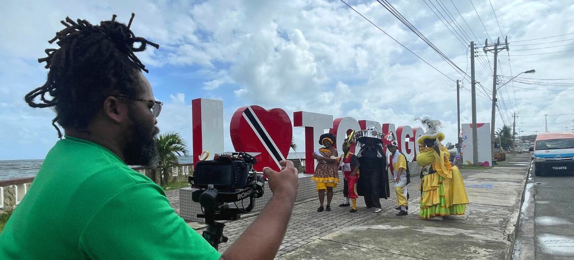 Seorang videografer memfilmkan para pemain Karnaval Inisiatif Terverifikasi di Tobago.