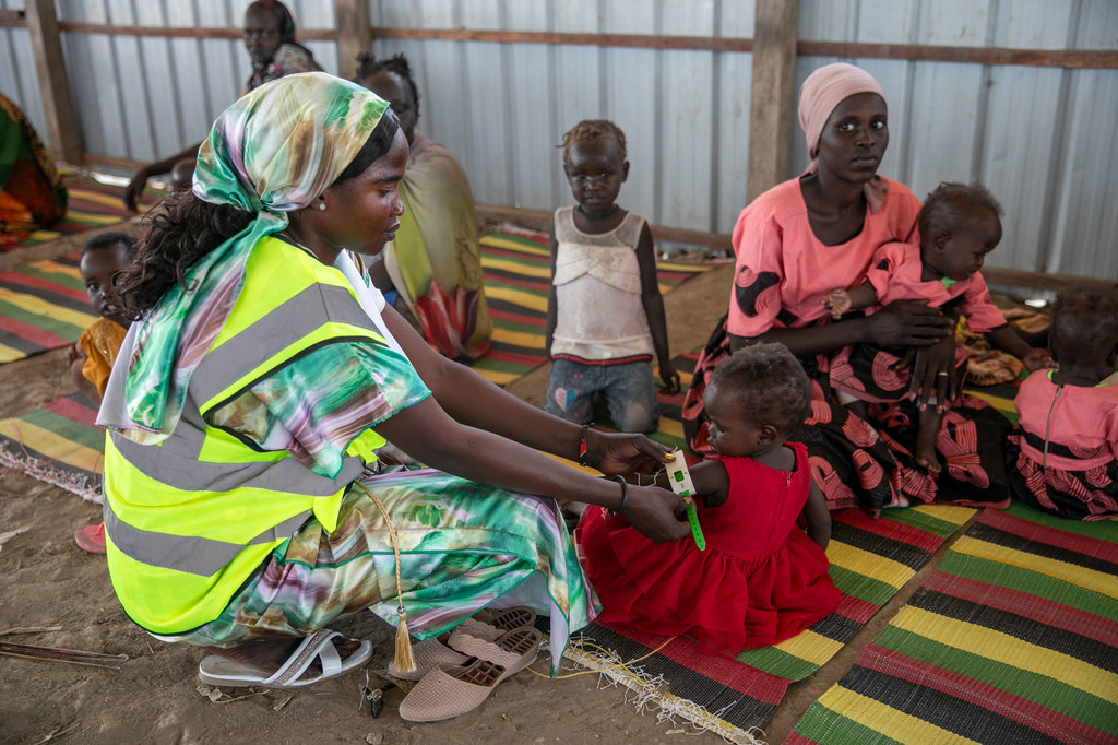Sudan Kusini. Mwanamke akimpima mtoto kwa ajili ya uchunguzi wa utapiamlo kwenye eneo la usambazaji wa misaada ya WFP.