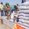 Des ouvriers déchargent des sacs d'aide alimentaire d'une barge sur un quai à Kosti, au Soudan.