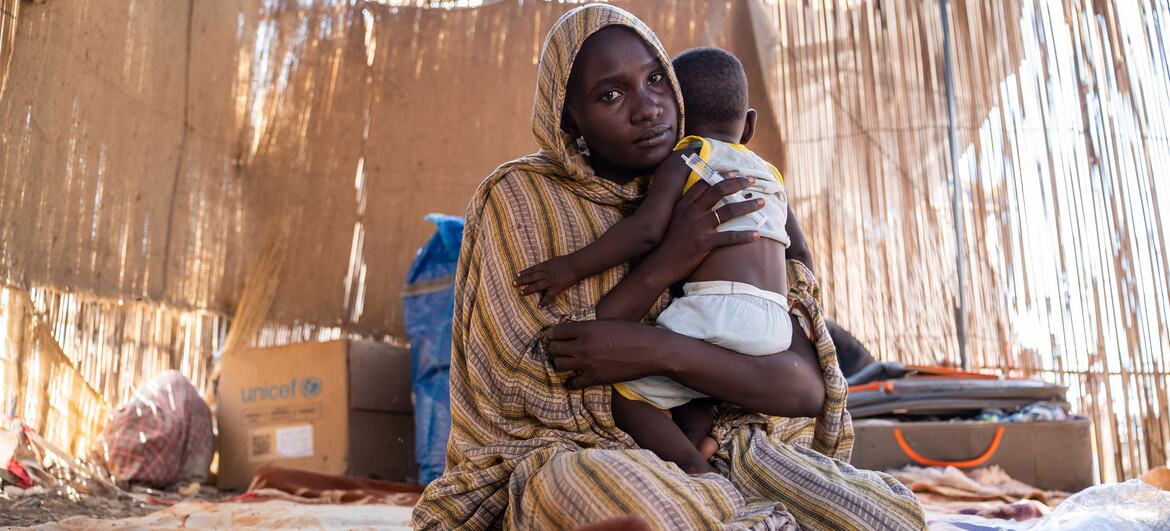 A woman, Mazaher, holds her one-year-old son Nassir, who is suffering from diarrhoea and vomiting, inside a makeshift shelter in Gedaref State, Sudan. The family fled conflict in Kordofan and received medical treatment from a UNICEF-supported mobile clinic.