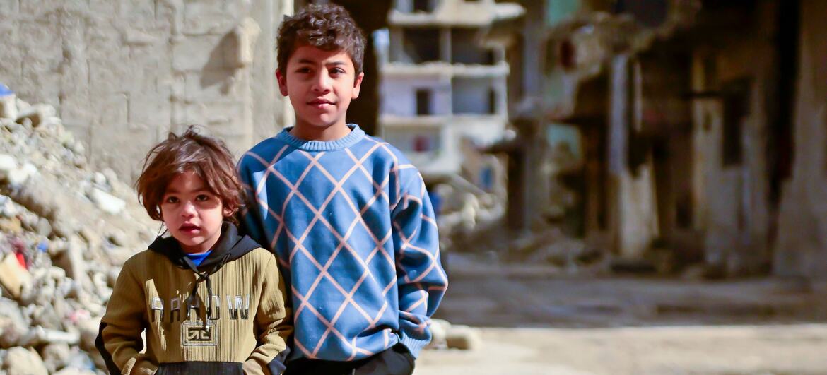 Two young Syrian children, Rami (10) and Noureddine (4), stand in front of damaged buildings in the Al-Tadamon neighbourhood of Damascus, Syria. The UNICEF-supported sewage rehabilitation project, funded by the German government through KfW Development Bank, has improved safety and living conditions for families in the area.