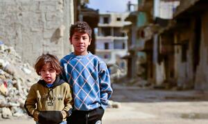 Two young Syrian children, Rami (10) and Noureddine (4), stand in front of damaged buildings in the Al-Tadamon neighbourhood of Damascus, Syria. The UNICEF-supported sewage rehabilitation project, funded by the German government through KfW Development Bank, has improved safety and living conditions for families in the area.