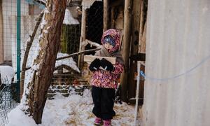 A four-year-old girl named Alika carries firewood in snowy conditions outside a house in the Kyiv region, Ukraine, to help light a wood-burning stove for warmth after being displaced by missile strikes.