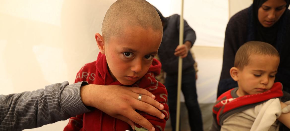 الطفل محمد (3 سنوات) في عيادة مدعومة من اليونيسف في إحدى الخيام بمدينة رفح في قطاع غزة. يجري المتخصصون فحوصا تتضمن قياس محيط ساقه لتقييم الوضع التغذوي لمحمد.