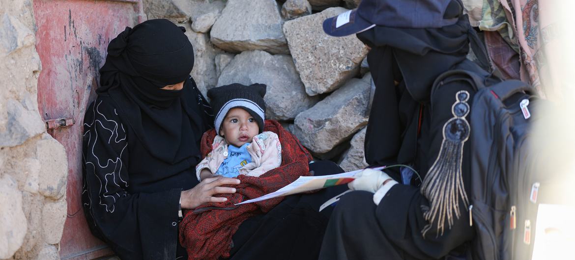 在也门的伊卜省，一名婴孩躺在母亲怀中。