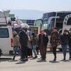 Сирийские и ливанские семьи, включая детей, прибывают на пограничный переход Юуссих в сельской части Хомса, Сирия, 10 марта 2026 года после пересечения из Ливана. Группа несет вещи, с автобусами и транспортными средствами вблизи. Делегация ЮНИСЕФ во главе с заместителем представителя программ Зейнаб Адамом оценивает ситуацию и услуги, поддерживаемые ЮНИСЕФ для перемещенных семей.