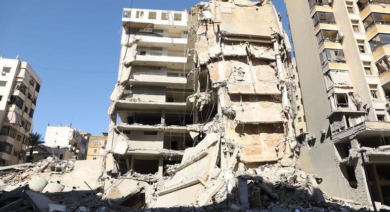 लेबनान के बेरूत के दक्षिणी उपनगर दहीह में एक बहुमंजिला इमारत को 9 मार्च, 2026 को हवाई हमलों के बाद भारी क्षतिग्रस्त और आंशिक रूप से ध्वस्त दिखाया गया है। मलबे और मलबे अग्रभूमि में जमीन पर बिखरे हुए हैं।