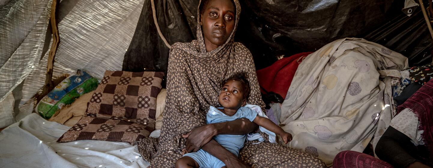 Halima, 30 ans, tient sa fille Samira, âgée de six mois, atteinte du syndrome de Down et récemment soignée pour malnutrition, à l'intérieur d'une tente dans un camp de déplacés à Tawila, au Darfour du Nord, au Soudan.