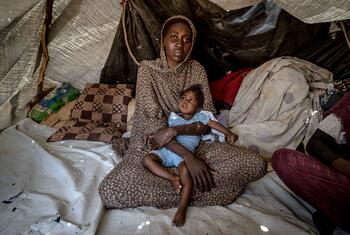 Halima, de 30 años, sostiene a su hija Samira, de seis meses, quien tiene síndrome de Down y fue tratada recientemente por desnutrición, dentro de una tienda de campaña en un campamento de desplazados en Tawila, Darfur del Norte, Sudán.