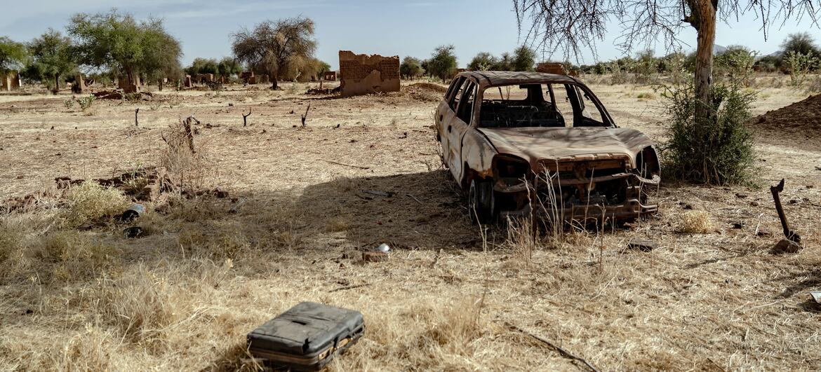 La carcasse calcinée d'une voiture et des maisons en torchis détruites dans le village abandonné d'Al Bakri, dans le Darfour du Nord, au Soudan, illustrant les conséquences du conflit et des déplacements.