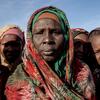 Retrato de mulheres e crianças sudanesas em um local de distribuição de uma cozinha comunitária da Save the Children no acampamento Daba Naira, em Tawila, Darfur do Norte, Sudão.