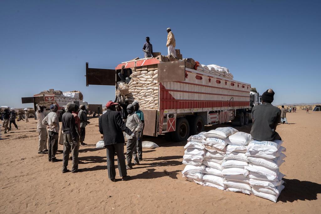 Trabajadores humanitarios y desplazados sudaneses descargan sacos de grano de trigo en un centro de distribución del Programa Mundial de Alimentos en el campamento de Daba Naira, en Tawila, Darfur del Norte, Sudán.