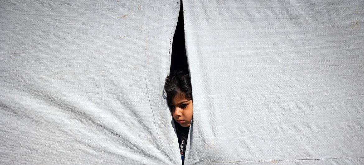 Um menino olha de dentro de uma tenda em Rafah, no sul da Faixa de Gaza