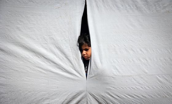 Un jeune garçon regarde depuis l’intérieur d’une tente à Rafah, dans le sud de la bande de Gaza.