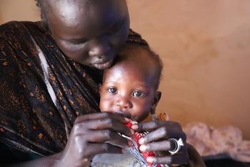 Une mère réfugiée tient son bébé dans ses bras tout en le nourrissant avec un sachet de complément nutritionnel à la frontière de Joda, au Soudan du Sud.