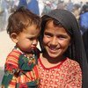 在阿富汗西南部坎大哈的一个流离失所者营地，一名七岁的女孩抱着她的妹妹。