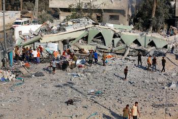 Pessoas caminham entre os escombros de um prédio destruído em Gaza.