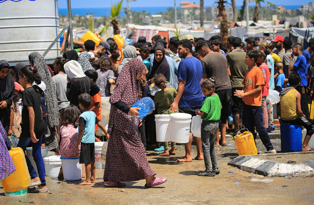 Des familles collectent de l'eau dans une installation soutenue par l'UNICEF à Deir al-Balah, dans la bande de Gaza.