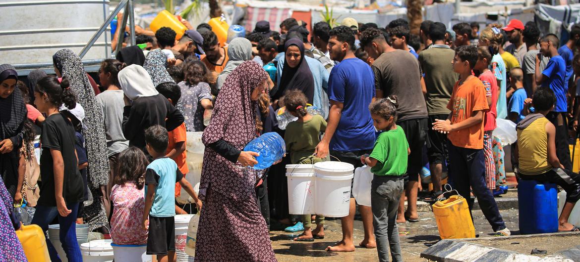 Families collect water from a UNICEF-supported facility in Deir al-Balah, in the Gaza Strip.