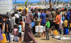 Families collect water from a UNICEF-supported facility in Deir al-Balah, in the Gaza Strip.