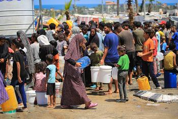 Families collect water from a UNICEF-supported facility in Deir al-Balah, in the Gaza Strip.