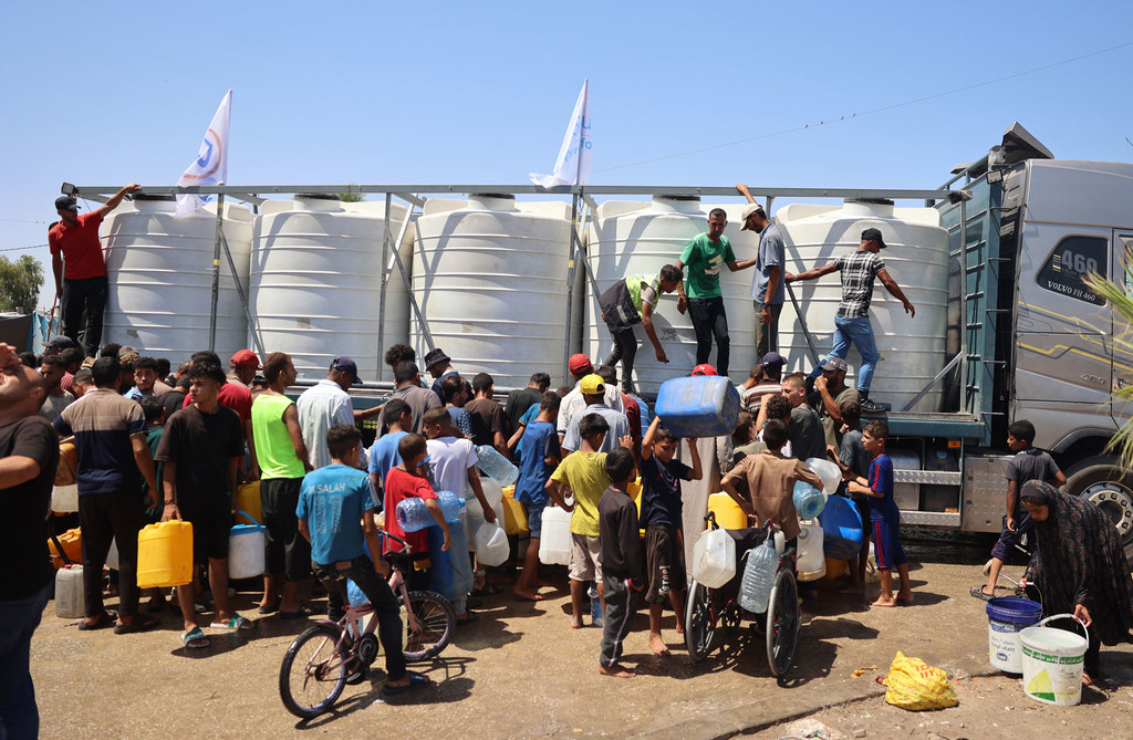 Niños y sus familias recogen agua de un depósito de agua apoyado por UNICEF en Deir Al-Balah, en la Franja de Gaza.