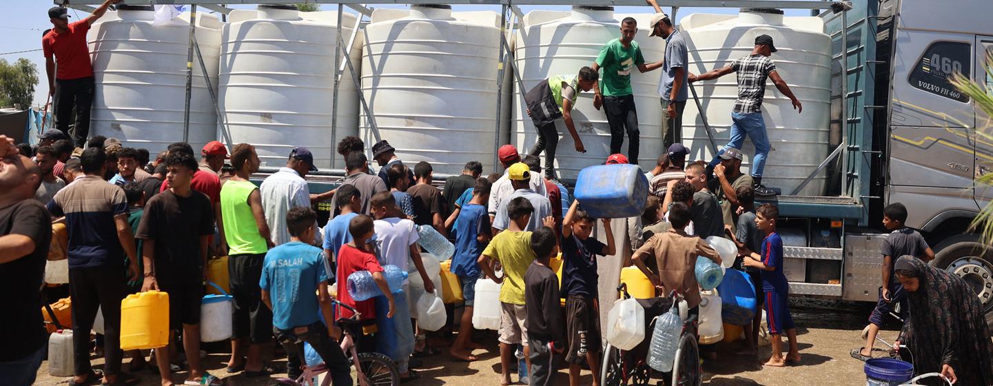 Children and their families fetching water from a UNICEF-supported water tank in Deir Al-Balah in the Gaza Strip.