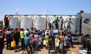 Children and their families fetching water from a UNICEF-supported water tank in Deir Al-Balah in the Gaza Strip.