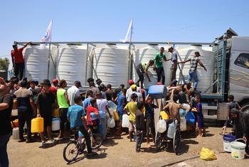 Семьи в Газе набирают воду, предоставленную при поддержке ЮНИСЕФ.