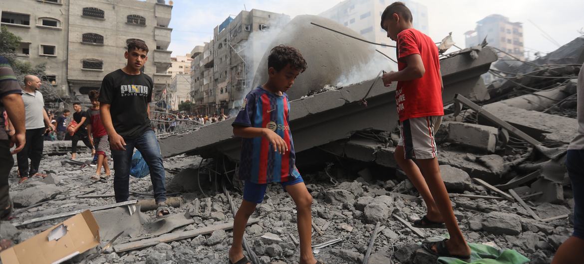 Children walk in the wreckage of homes destroyed by airstrikes in Al Shati refugee camp in the Gaza.