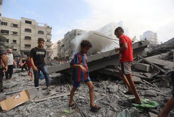 在加沙的难民营，孩子们走在被空袭摧毁的房屋的废墟中。