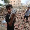 A five-year-old boy holds up his cat  amidst the wreckage of his home in Gaza.