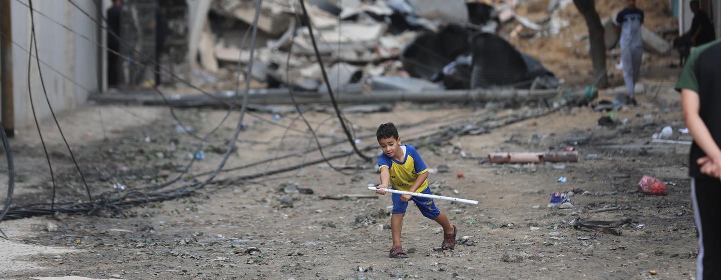 Un jeune garçon joue dans la rue au milieu des décombres des maisons détruites par des frappes aériennes dans le camp de réfugiés d'Al Shati, dans la bande de Gaza.