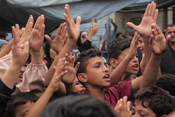Children in Gaza raise their hands and cheer while celebrating the announcement of a ceasefire.