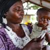 Una madre sostiene a un niño pequeño que está comiendo una bolsa de harina fortificada como parte de un proyecto piloto del PMA para prevenir la desnutrición en la República Centroafricana.