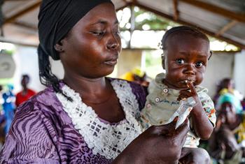 Una madre sostiene a un niño pequeño que está comiendo una bolsa de harina fortificada como parte de un proyecto piloto del PMA para prevenir la desnutrición en la República Centroafricana.