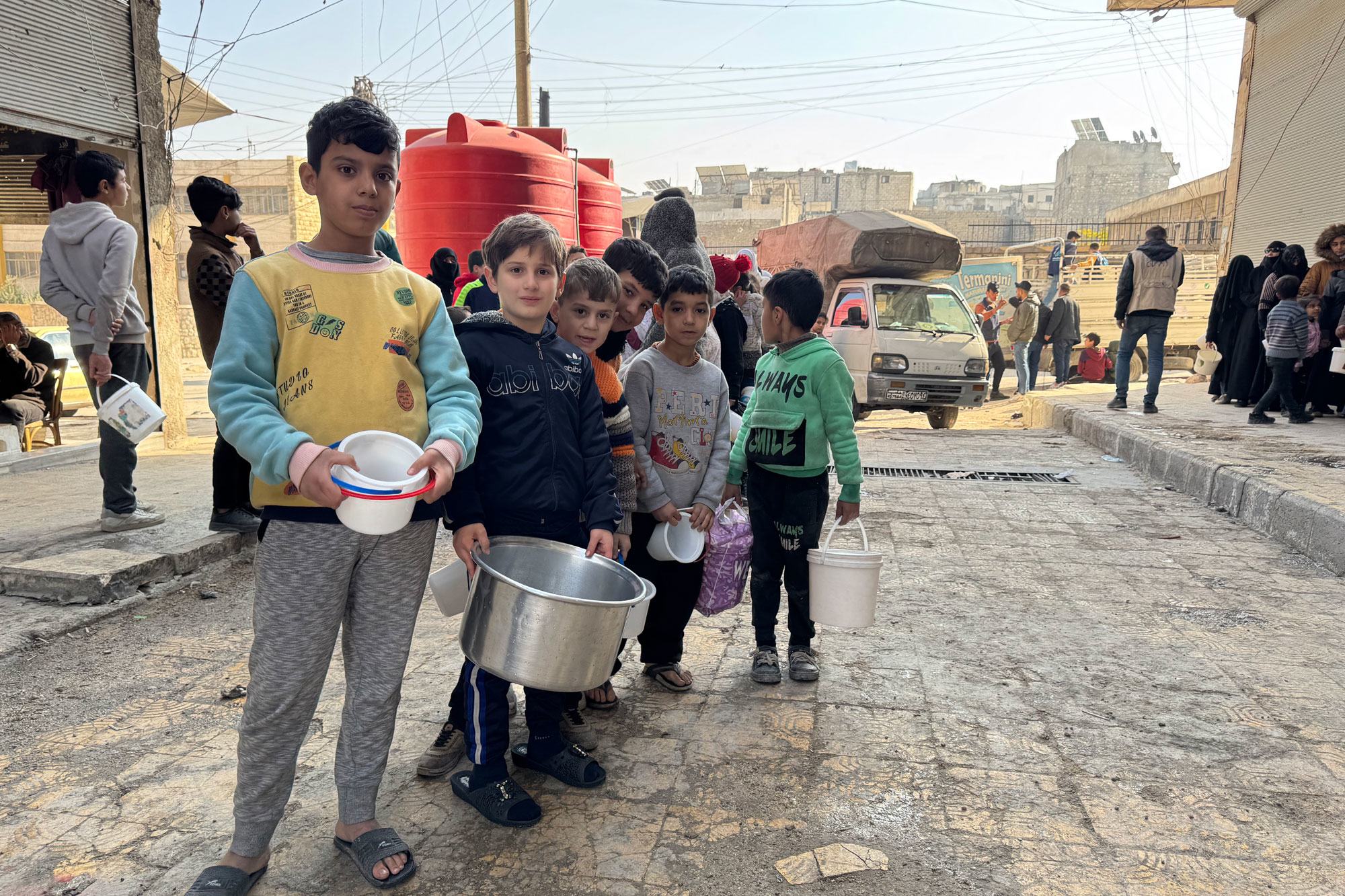 أطفال سوريون يحملون أوعية ودلاء خلال عملية توزيع مواد غذائية في حلب، سوريا، في 9 ديسمبر 2024.
