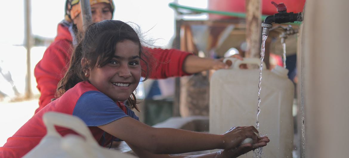 شمالی شام میں پناہ گزینوں کے کیمپ میں ایک بچی اپنے ہاتھ دھوتے ہوئے۔