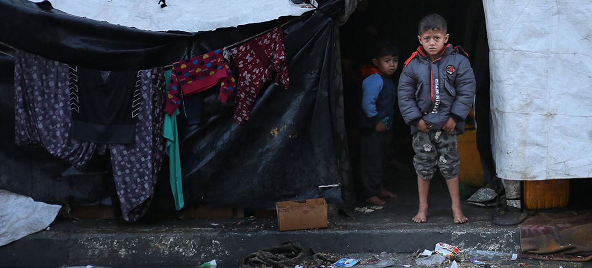 Un garçon se tient pieds nus devant une tente où réside sa famille après avoir été déplacée vers la ville de Rafah, au sud de la bande de Gaza.