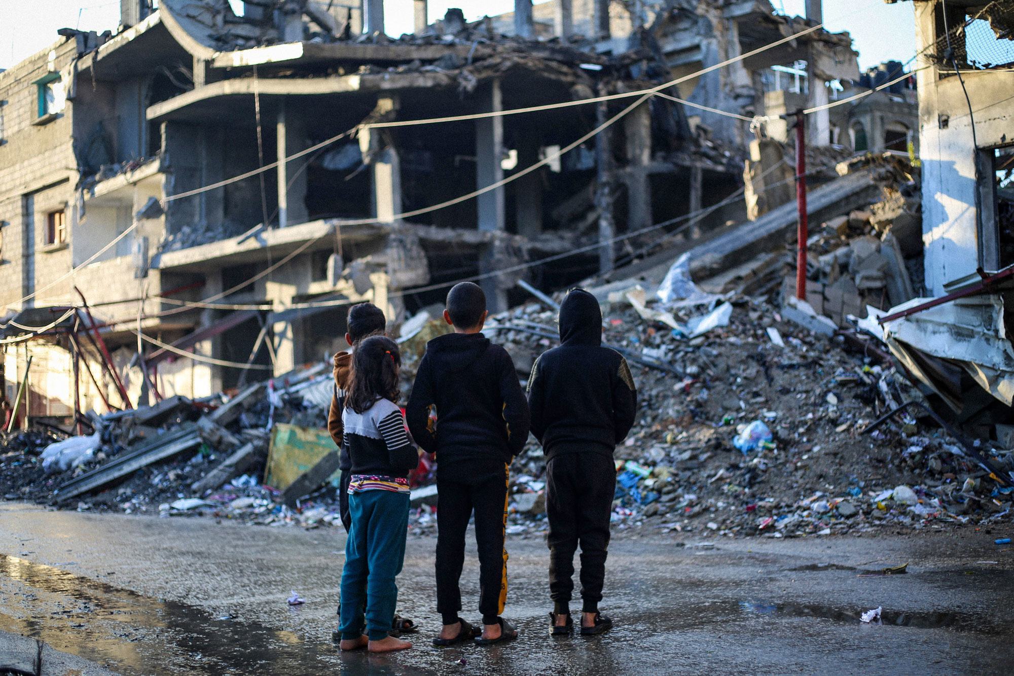 أطفال في غزة يقفون أمام منزل مدمر بفعل قصف بمدينة رفح، جنوب القطاع.