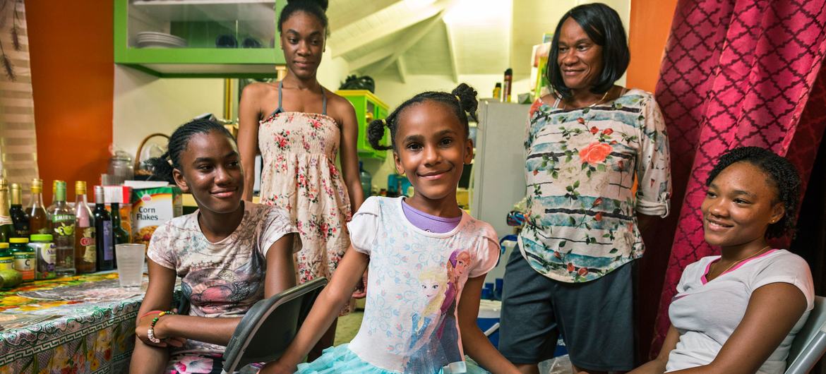 A family of five, including a mother and four daughters, poses for a photo in their rented home in St. John's, Antigua. The family was displaced from Barbuda after Hurricane Irma.