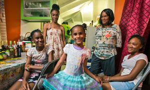 A young girl shows off her dress in front of her family at home on the island of Antigua, in the Caribbean.