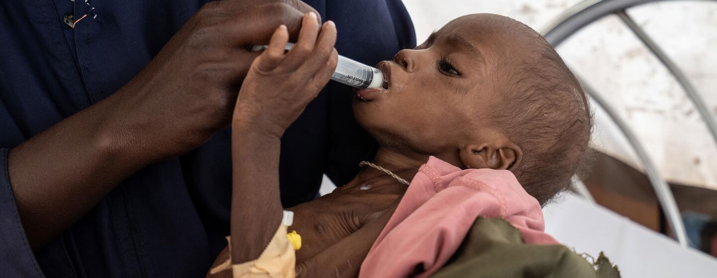 Mona, une enfant de trois ans gravement malnutrie, est nourrie à la seringue par un professionnel de santé à l'hôpital de Paris géré par MSF à Tawila, au Darfour du Nord, au Soudan, en février 2026.